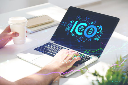 Digital graph rising and falling, screen with initial coin offering icons, and hand with a coffee...