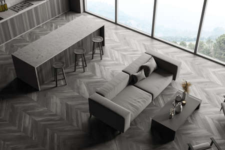 Black wooden interior of kitchen, from above, bar chairs and table, gray sofa with pillows. Windows...