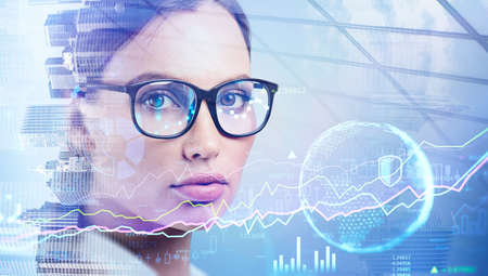 Portrait of businesswoman, trader or financial analyst wearing glasses and looking straight toward the camera. Double exposure. Finance chart and statistics. New York on backgroundの写真素材