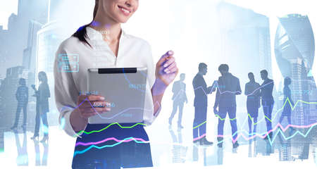 Businesswoman with tablet in hand, silhouettes of diverse business people, skyscrapers and graph lines with numbers. Concept of modern work office with managers, partnersの写真素材