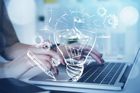Businesswoman hands fingers typing on laptop keyboard, drawing of bulb with mountain top, double exposure with skyscrapers. Concept of new ideas, technology, successの写真素材