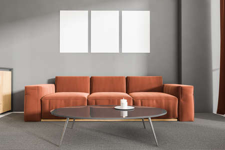 Home interior with couch on gray carpet, coffee table with candle. Minimalist light room with three mockup copy space frames above sofa, 3D renderingの写真素材