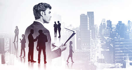 Office man in suit with clipboard in hands and business document, double exposure of business buildings and people. Concept of contract and international companyの写真素材
