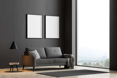 Living room interior with large panoramic window that has a brilliant view on the countryside. The black wall is decorated with two posters. Dark sofa is on the wooden parquet. Mock up. 3d renderingの写真素材