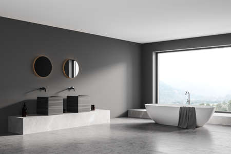 Dark gray bathing room with white bathtub and gray towel, two sinks with mirrors on concrete floor. Luxury minimalist bathroom interior with window on countryside, 3D renderingの写真素材