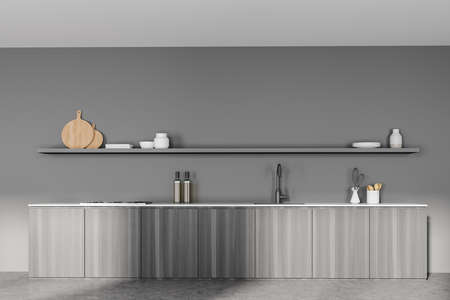 Gray wooden minimalist kitchen interior with kitchenware and rack, front view. Long minimalist cooking table set on concrete floor, 3D renderingの写真素材