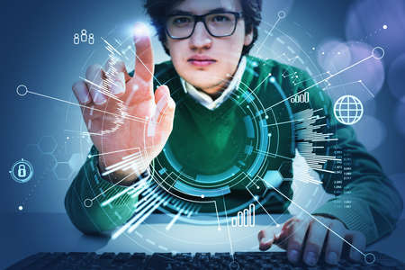 Young man wearing green jumper is sitting at the workplace, typing on the keyboard and touching the...