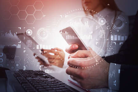 Businessman and businesswoman with smart phone and tablet in their hands are sitting at the office...