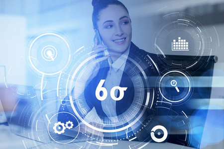 Businesswoman talking phone and working on laptop researching six sigma, quality control and...