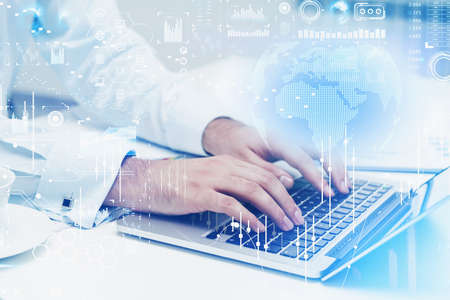 Businessman hands using laptop on the office table. Stock market changes candlesticks, data...