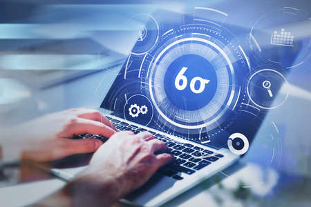 Businessman working on laptop and researching six sigma, quality control and manufacturing process management concept in business. virtual interface with cogwheels.の写真素材