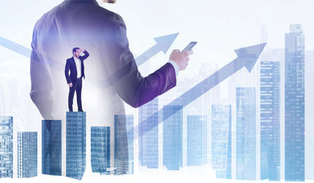 Man in suit using smartphone, climbing bar chart, looking at great distance. Double exposure with...