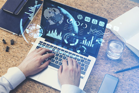Office man hands on keyboard, devices on the table, top view. Virtual screen with stock market...