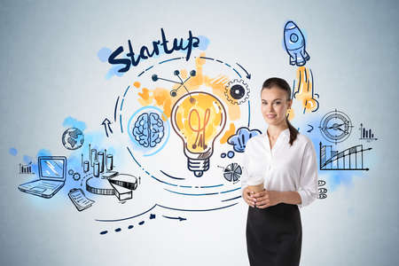 Business woman happy smiling with coffee cup, colorful doodle icons and lightbulb on light blue wall. Drawing with arrows, rocket, pie chart and network icons. Concept of fresh idea and business planの写真素材
