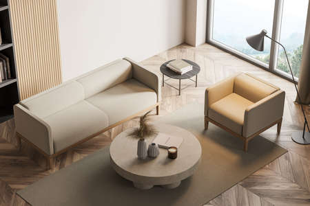 Beige room interior with armchair and sofa on wooden floor. Top view of coffee table with books and...
