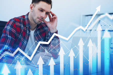 A man in casual clothes taking notes into notebook checking the information in laptop. Double exposure with white growing arrows. Positive dynamics and lines. Concept of technology and financeの写真素材