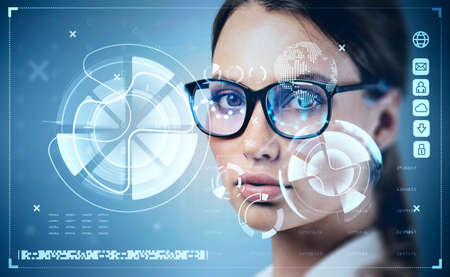 Serious businesswoman wearing formal suit and glasses is watching at digital interface with hologram...