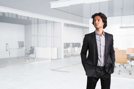 Portrait of confident handsome businessman in black suit, hands in pockets. Modern international...