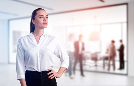 Office woman confident look, standing hand to waist near business conference room with people, double exposure. Concept of business workers, secretary in international companyの写真素材