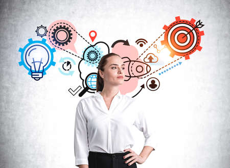 Young office woman confident look in white shirt, near drawing with gears and target. Process of thinking icons on concrete background. Task and goal, concept of human intelligence and planの写真素材