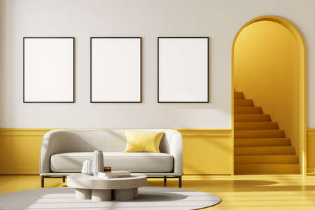 Apartment interior with white couch and coffee table on carpet with yellow floor. Mockup blank wall copy space with three posters, staircase with arch door, 3D renderingの写真素材