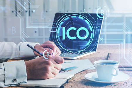 Businessman or cryptocurrency trader analyzing bitcoin rates after ICO, using laptop and taking...