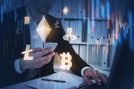 Businessman using laptop and smartphone to research a business report of cryptocurrency market...