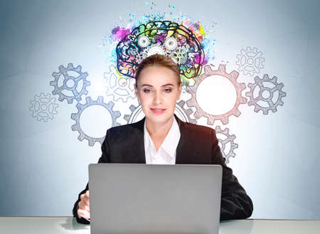 Office woman, boss in black suit working with laptop, sketch of cogwheels and colorful brain on blue background. Concept of business education and start upの写真素材