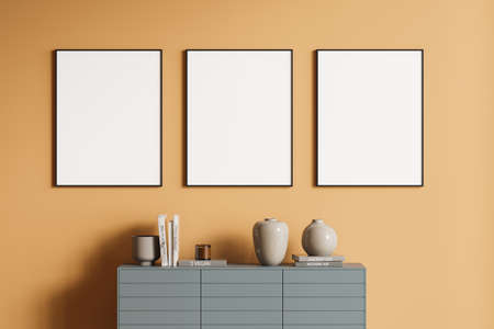 Interior of stylish living room with orange walls, gray cabinet and row of three vertical mock up...