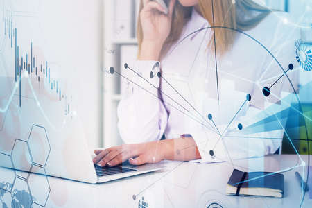 Businesswoman or stock trader analyzing stock market graph chart using laptop and talking smarphone...