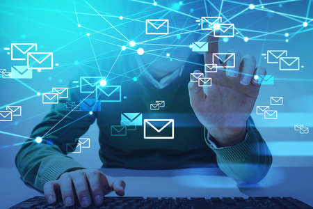 Young man with hand on keyboard, finger point at hologram of many inbox emails and network online...