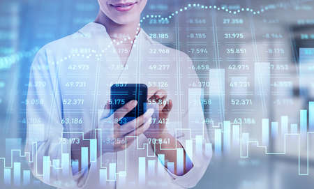 Businesswoman checking stock market rates in smartphone. Hologram charts. Business and financial...