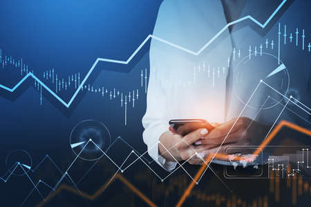 Businesswoman trader in white shirt working adn checking quotes using smart phone. Forex graph...