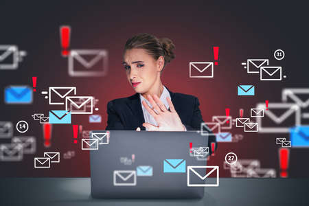 Businesswoman wearing suit is sitting at workplace looking at laptop screen and showing stop gesture by hand as concept of stop spam mails. Concept of insecure of personal data.の写真素材