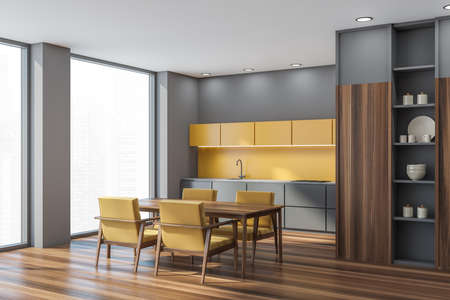 Interior with the yellow and gray kitchen area, wooden cabinet and flooring. Corner view on table with four armchairs at the panoramic windows. Niche with shelf for decor crockery. 3d renderingの写真素材