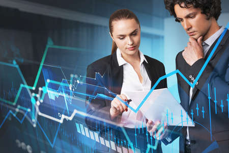 Businessman and businesswoman looking into notes. Stock market graph changes, candlesticks and...