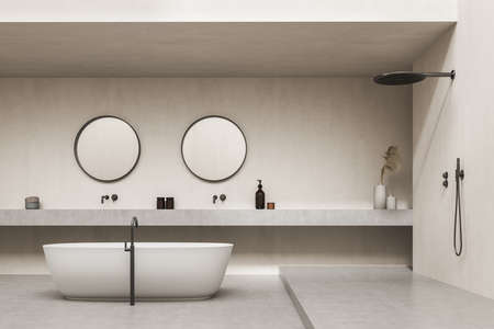 Luxury beige bathroom space with two original round mirrors above washbasins, oval tub and open...