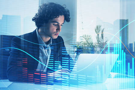 Handsome Hispanic businessman trader in formal suit working on laptop and checking quotes and...