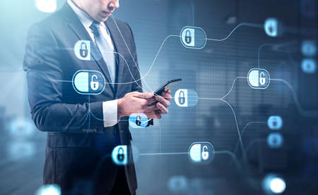 Businessman in formal suit is browsing the Internet in smartphone. Blue glowing information protection padlock icons. Concept of cyber security and data storageの写真素材