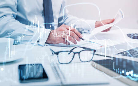 Businessman trader is sitting at workplace and working with documents to continue trading...