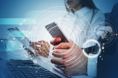 Businessman and businesswoman wearing formal suit are holding smartphone and tablet in hands. Office in the background. Digital interface hologram in foreground. Concept of teamwork and cooperationの写真素材