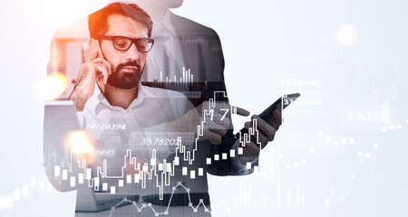 Two businessman wearing formal suit and white shirt working using smartphone analyzing stock market behavior. Concept of cooperation, teamwork, communication and network for successful tradingの写真素材