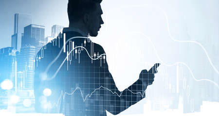 Silhouette of businessman wearing formal suits working on the smartphone analyzing stock market...