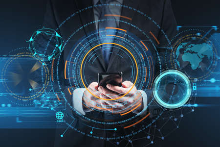Businessman wearing formal suit is holding smartphone with digital interface hologram in his hand....