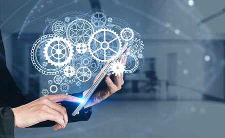 Businesswoman wearing formal suit is touching the screen of tablet with digital interface. Blurred...
