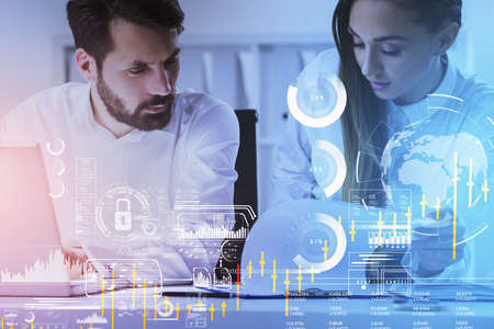 Businessman and businesswoman work together on laptop and looking at clipboard. Office in the...