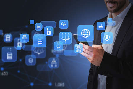 Businessman wearing formal suit is holding smartphone with digital interface with hologram of globe,...