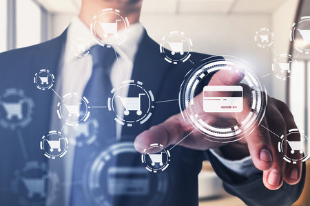 Businessman wearing formal suit is touching screen with interface with icons of credit card and cart. Office workplace in the background. Concept of online buying and purchasingの写真素材