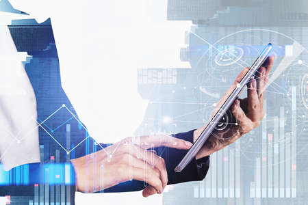 Businesswoman wearing formal suit is holding a tablet with digital interface with hologram of...