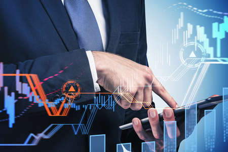 Businessman wearing formal suit is holding tablet and touching it with his finger. Blue background....